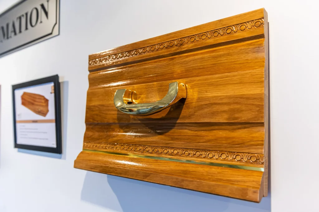 Échantillon de cercueil en bois sculpté avec poignée dorée.
