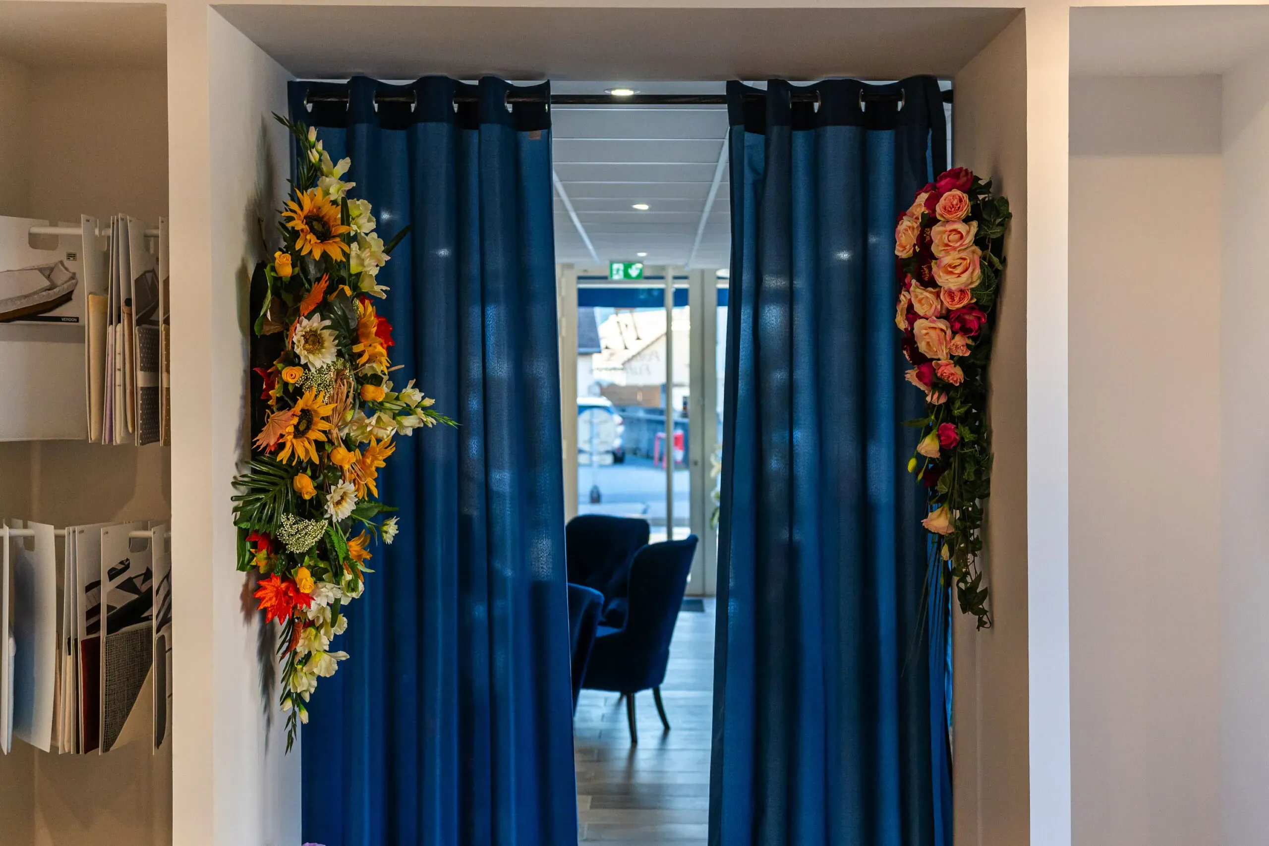 Entrée décorée avec d'élégants rideaux bleus et compositions florales.